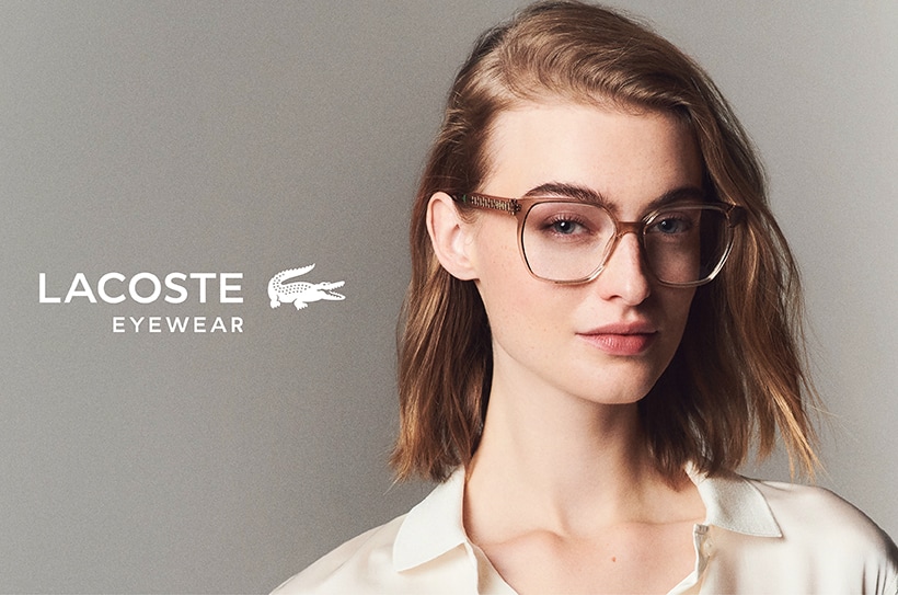 Femme aux cheveux châtain clair mi-longs portant des lunettes correctrices Lacoste transparentes, sur fond gris.