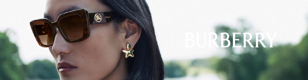 Vrouw met grote rechthoekige Burberry-zonnebril met havannamontuur en gouden oorbellen, buiten.