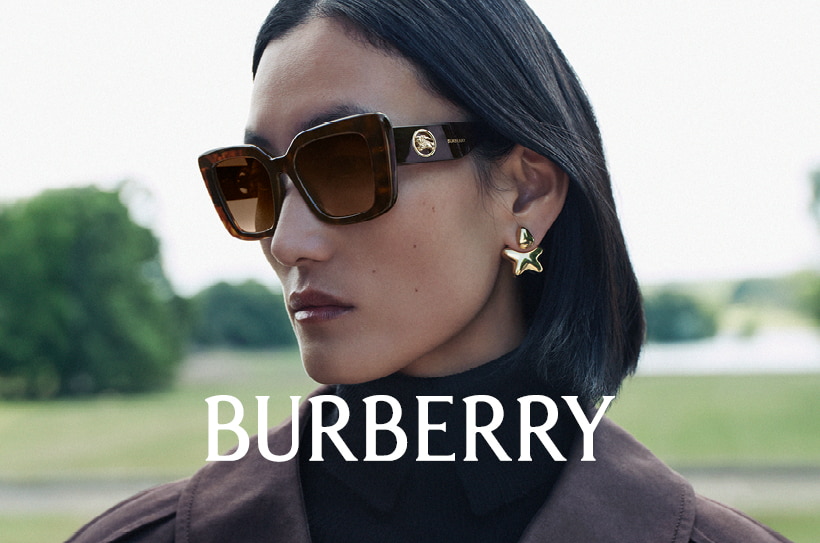 Vrouw met grote rechthoekige Burberry-zonnebril met havannamontuur en gouden oorbellen, buiten.