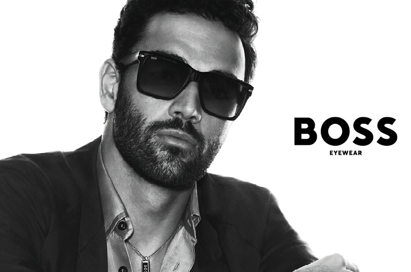 Portrait noir et blanc stylé d’un homme avec des lunettes de soleil élégantes et un look distinctif.