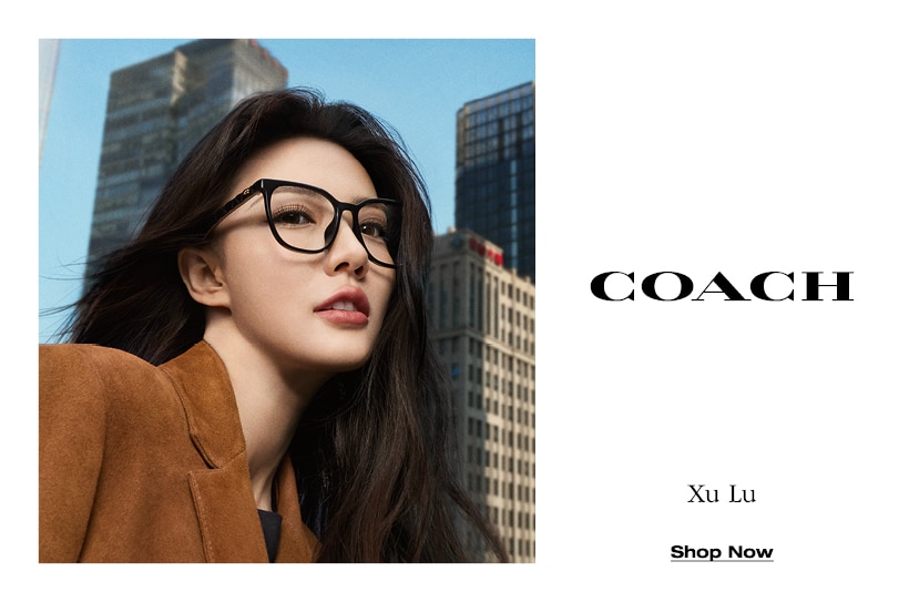 Vrouw met lang, donker haar draagt een zwarte Coach-correctiebril en een bruine blazer; op de achtergrond moderne hoogbouw onder een blauwe hemel; rechts in beeld het Coach-logo.
