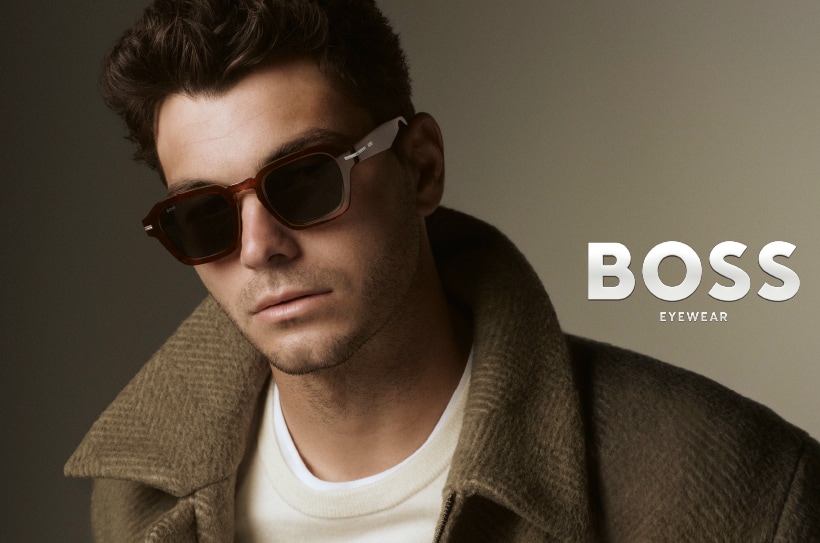 Homme aux cheveux courts portant des lunettes de soleil rectangulaires BOSS Eyewear et un manteau.