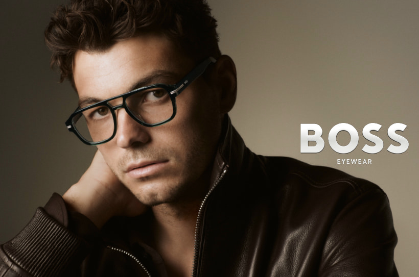 Man met kort haar draagt een rechthoekige bril van BOSS Eyewear en een leren jas.