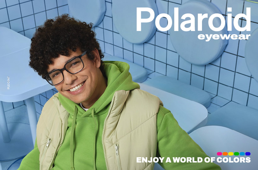 Lachende man met Polaroid bril, groene hoodie en beige bodywarmer in blauwe ruimte.