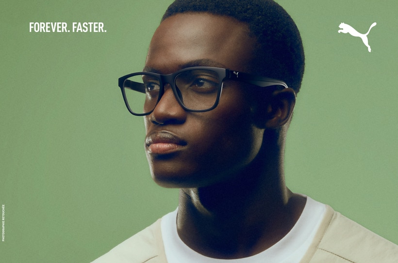 Jeune homme avec lunettes Puma noires sur fond vert; logo et slogan “FOREVER. FASTER.” en haut.