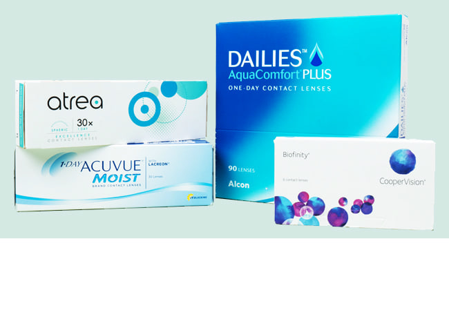 Des emballages de lentilles journalières et mensuelles sur la table, avec une salle de bain en arrière-plan.