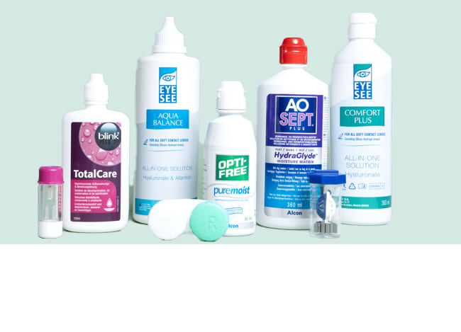 Des flacons de solution pour lentilles de contact sur la table, avec une salle de bain en arrière-plan.