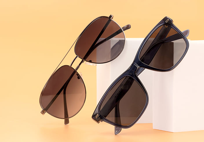 Deux lunettes de soleil, l\'une avec une monture pilote en métal et l\'autre avec une monture carrée en plastique noir, sur un fond orange.