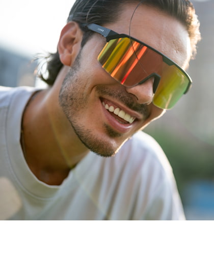 Man met moderne sportieve zonnebril met spiegelglazen, lachend in de zon.