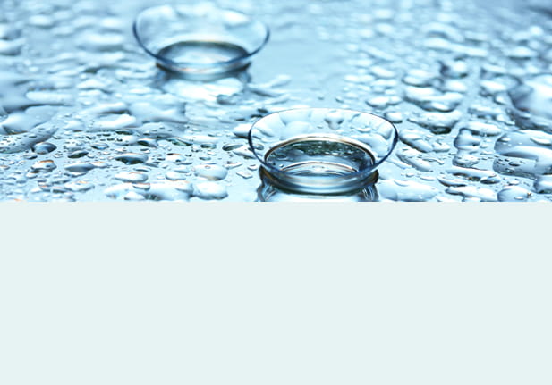 Twee contactlenzen op een nat oppervlak met waterdruppels.